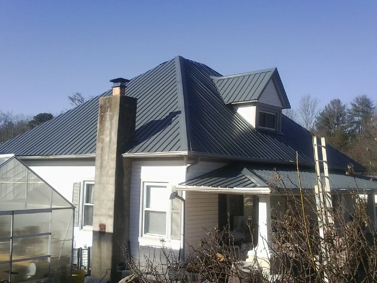 Dark blue standing seam metal roof on a white farmhouse with dormer — Slate & Tile Roof Repair by Roofing Brothers in West Newbury