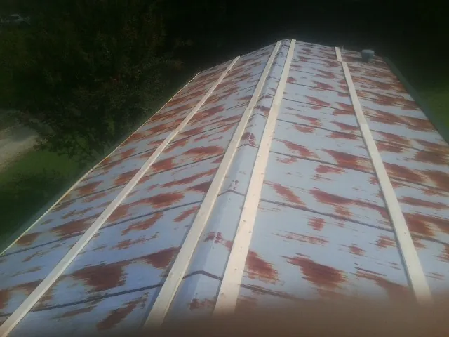 Rusted metal roof panels with new wood purlins before replacement — Storm Damage Roof Repair in West Newbury by Roofing Brothers
