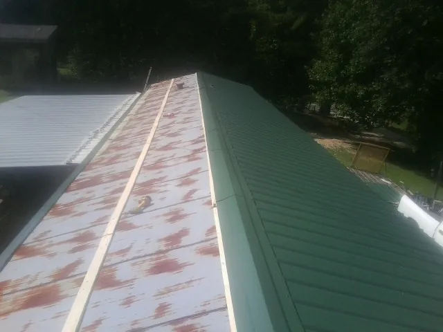 Old rusted panels beside newly installed green metal roofing — Wind Damage Roof Repair by Roofing Brothers in West Newbury