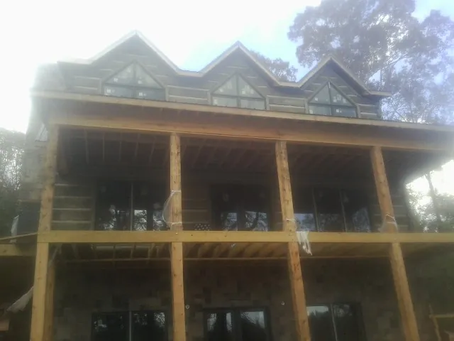 Dormers and porch framing on a large log home under construction — Roof Coating work by our crew in West Newbury