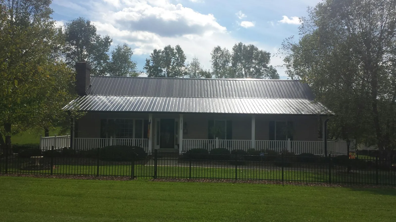 Gray metal roof on a brick ranch with a full width front porch — Gutter Guard Installation work by our crew in West Newbury