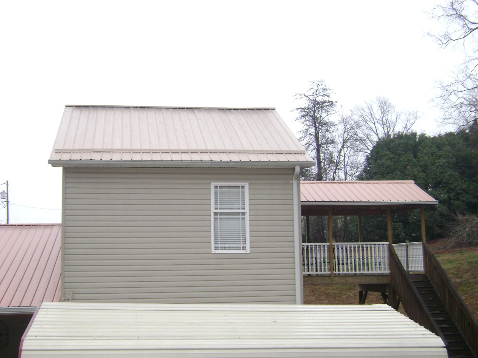 Tan metal roofs on a two story addition and attached porch, from a Roof Replacement job in West Newbury
