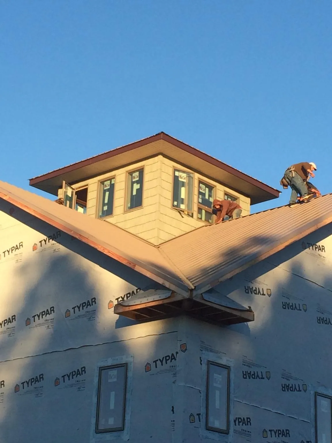 Roofers working around a rooftop cupola on a new metal roof at sunset — Roof Waterproofing in West Newbury by Roofing Brothers